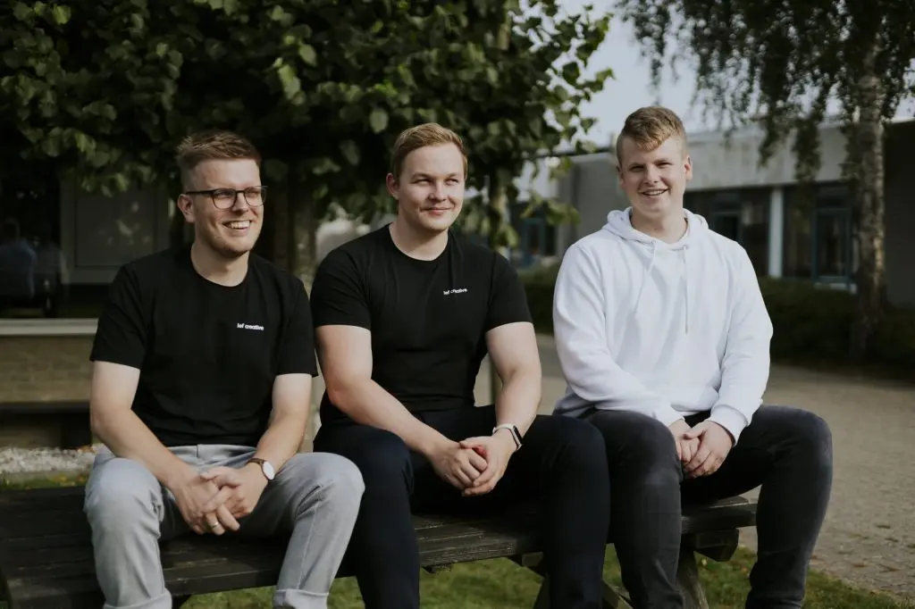 Het team van Lef Creative op een bankje buiten het kantoor
