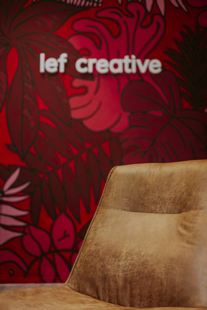 Lef Creative logo on a red floral wall at the office